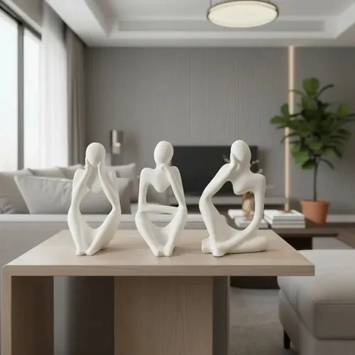 Set of three white plaster thinker figurines in different seated poses